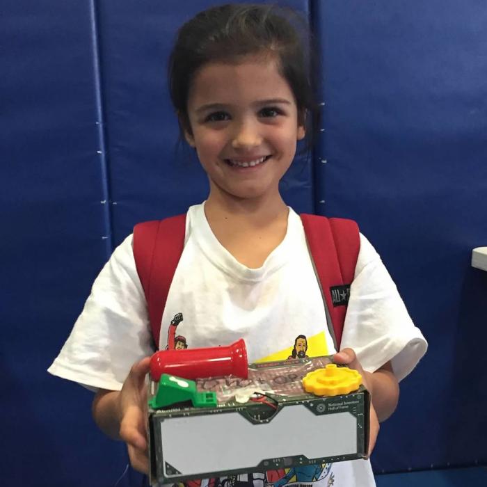 Delaney DeMarco as a child proudly holds up the invention prototype she made at Camp Invention