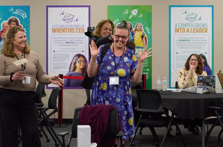 An excited educator wearing a starry dress smiles and waves during a professional development exercise
