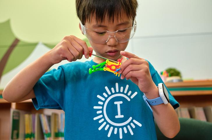 A Camp Invention camper uses a screwdriver to take apart a colorful robot