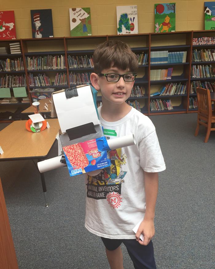 Scott Dunn as an elementary student holds up an invention prototype he created using recyclable materials