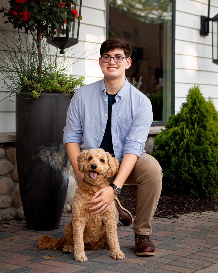 Scott Dunn smiles outside with a small fluffy dog