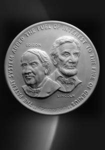 A medal featuring Thomas Edison and Abraham Lincoln with the quote “the patent system added the fuel of interest to the fire of genius”