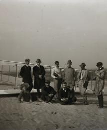 Group portrait in front of glider at Kill Devil Hill. Sitting: Horace Wright, Orville Wright, and Alexander Ogilvie; standing: Lorin Wright, and group of journalists, including Van Ness Harwood of the New York World, Berges of the American News Service, Arnold Kruckman of the New York American, Mitchell of the New York Herald, and John Mitchell of the Associated Press.