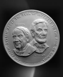 A medal featuring Thomas Edison and Abraham Lincoln with the quote “the patent system added the fuel of interest to the fire of genius”