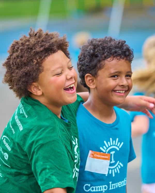 Two Camp Invention campers laugh as they participate in outdoor games