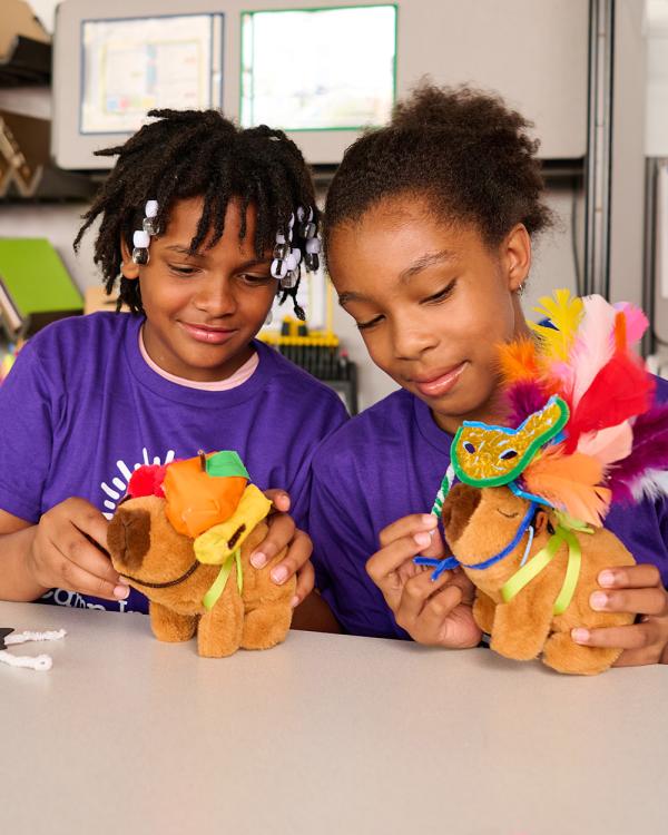 Two Camp Invention campers show off the costumes they crafted for their robotic capybaras