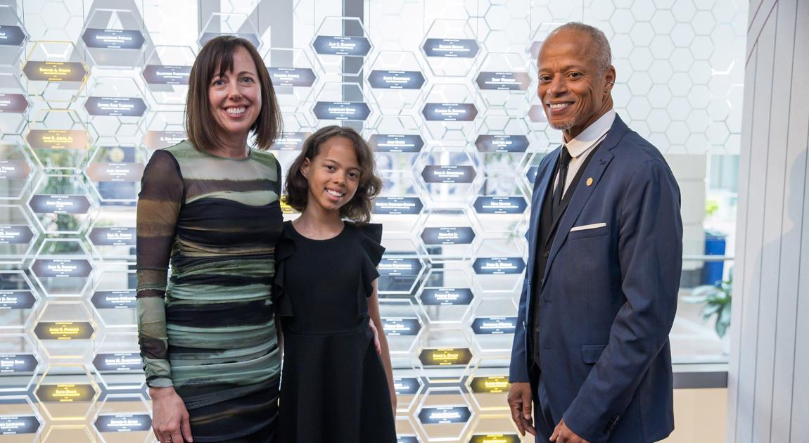 Kerrie Holley smiles in front of the Gallery of Icons exhibit with his family