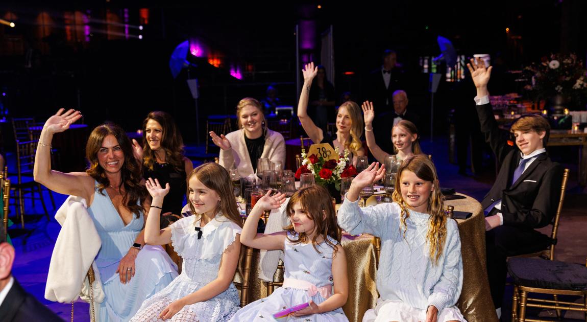 A table of young audience members wave during the Induction Ceremony