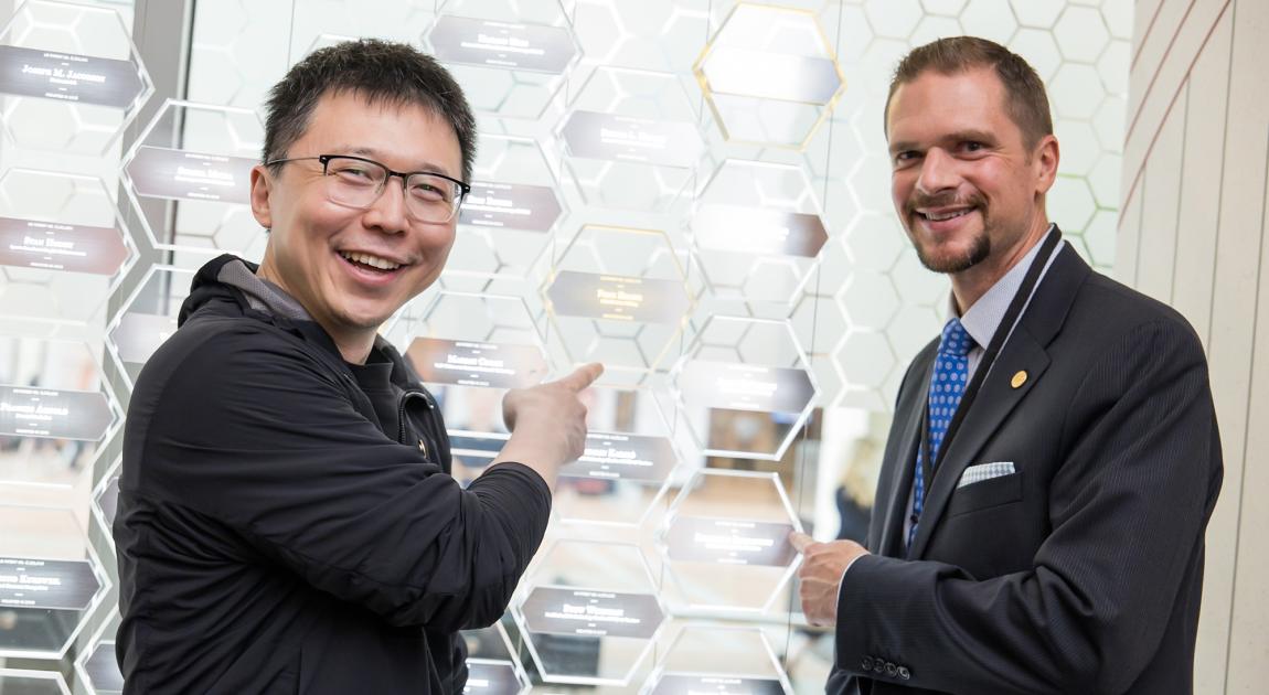 Feng Zhang and Rodolphe Barrangou smile and point to their plaques in the Gallery of Icons